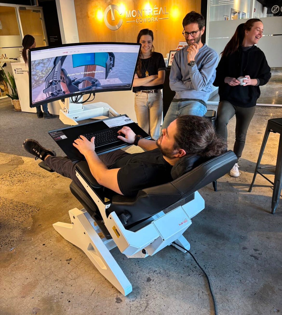 Person using a unique chair with a computer setup in a modern office setting.